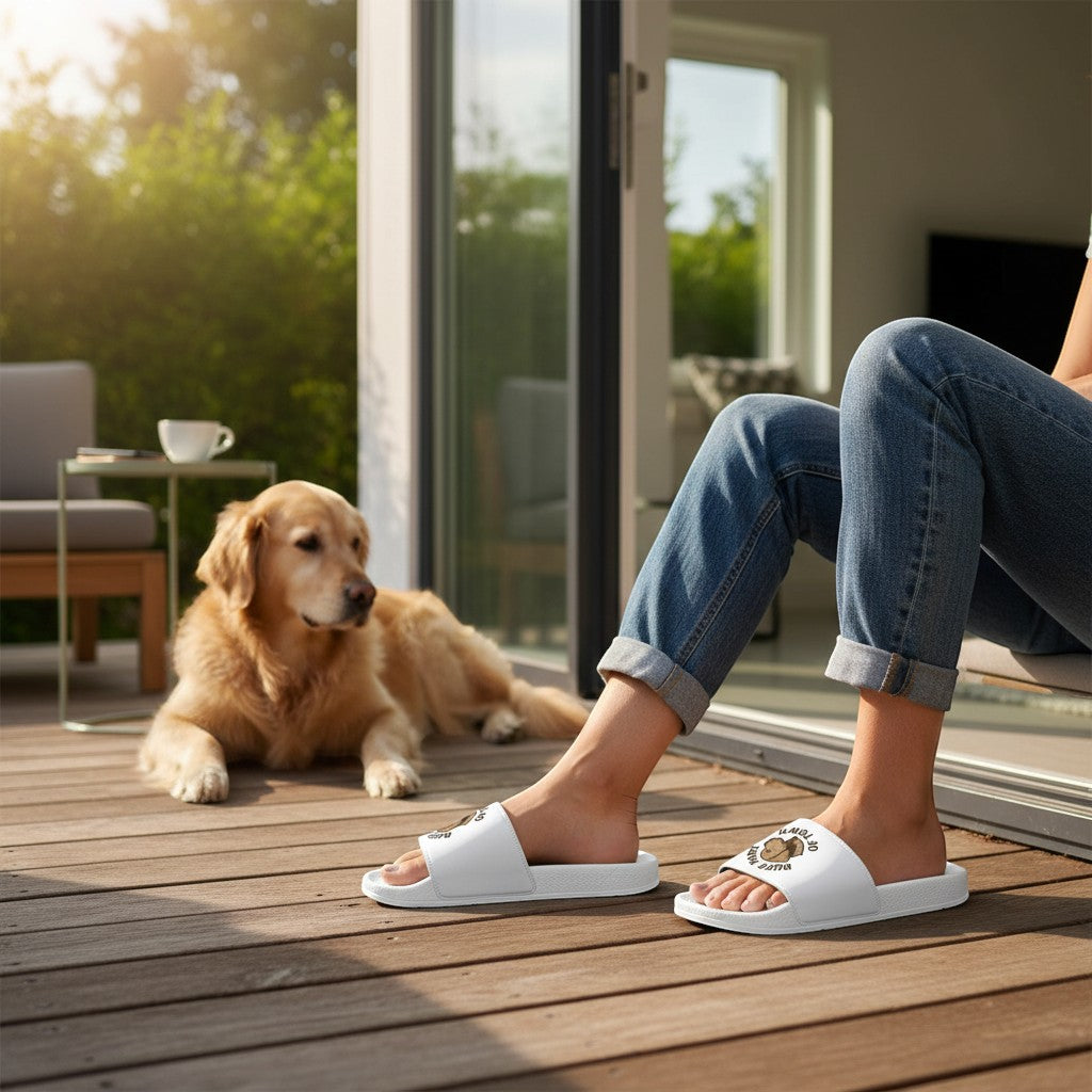 Ruff Part of Town white slide sandals with removable straps featuring a dog patch. Worn by a person in jeans sitting on a wooden deck.